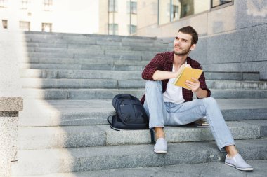 Merdivenlerde oturan, not yazma ve açık havada rüya öğrenci