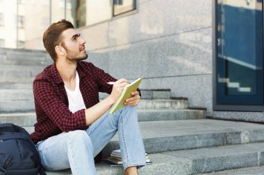 Merdivenlerde oturan, not yazma ve açık havada rüya öğrenci