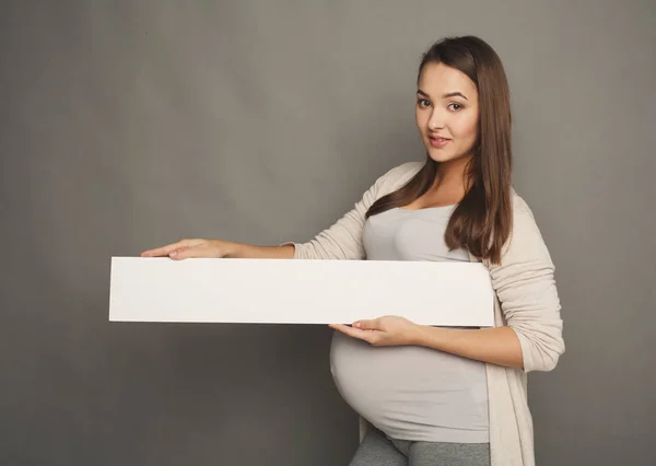 Молода вагітна жінка з чистим білим папером — стокове фото