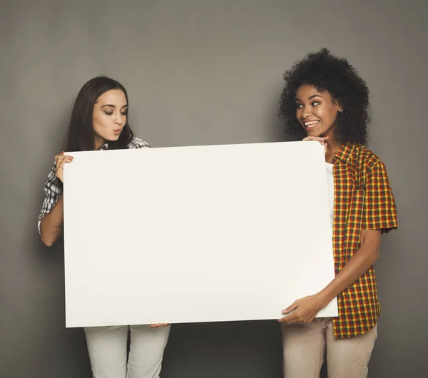 Two girlfriends holding blank white banner — Stock Photo, Image