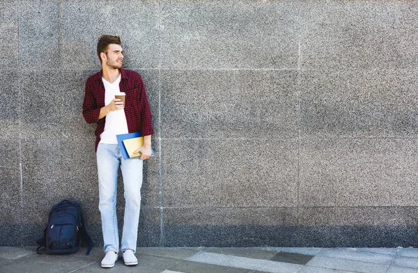 Atractivo estudiante con taza de café sobre fondo gris al aire libre —  Fotos de Stock