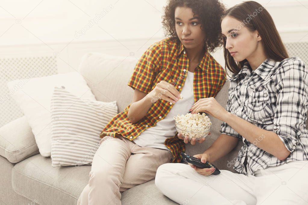 Interested young women watching TV at home