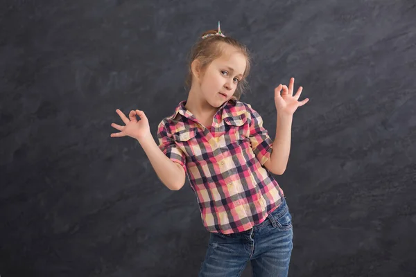 Fröhliches kleines Mädchen hat Spaß bei grauem Hintergrund — Stockfoto