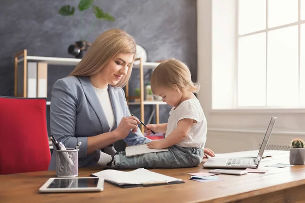 Jonge moeder bedrijf baby tijdens het schrijven van notities — Stockfoto