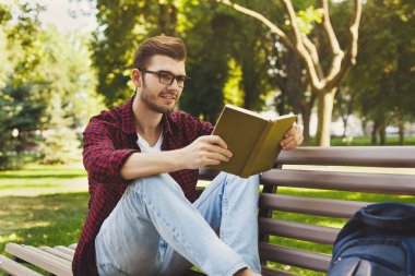 genç adam açık havada bir kitap okuma