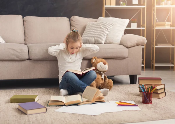 Meisje met boek en haar favoriete speeltje thuis — Stockfoto