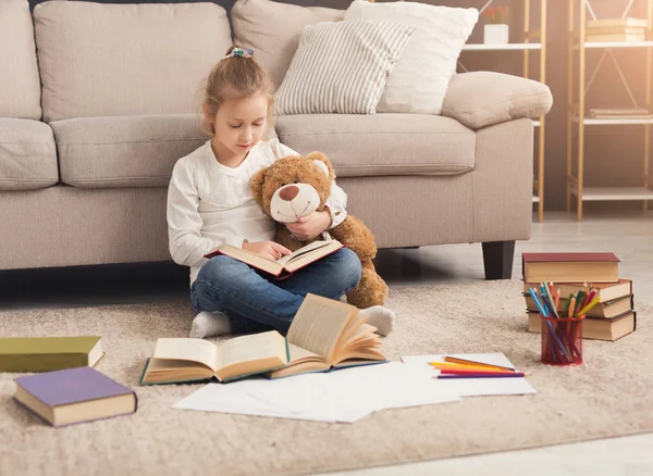 Šťastné dítě malé ženské objímání její medvídek a čtení — Stock fotografie