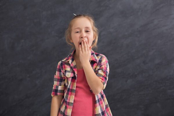 Little girl yawning on dark background