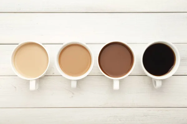 Diverse koffie kopjes op wit hout, top uitzicht — Stockfoto
