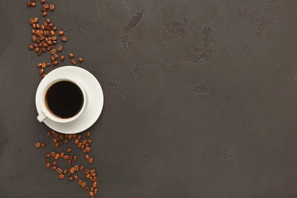 Cup of black coffee and scattered beans on gray background — Stock Photo, Image