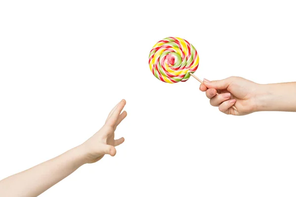 Kid hand reaching for big colorful lollipop — Stock Photo, Image