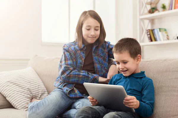 Twee kinderen met gadgets op de Bank thuis — Stockfoto