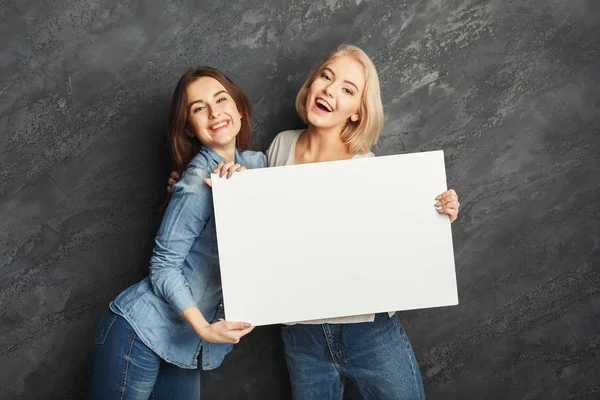 Filles heureuses avec bannière blanche vierge au fond sombre studio — Photo