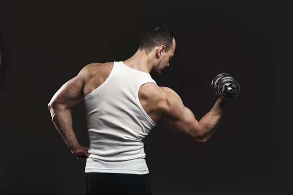 Hombre atlético fuerte con mancuerna muestra el cuerpo muscular — Foto de Stock