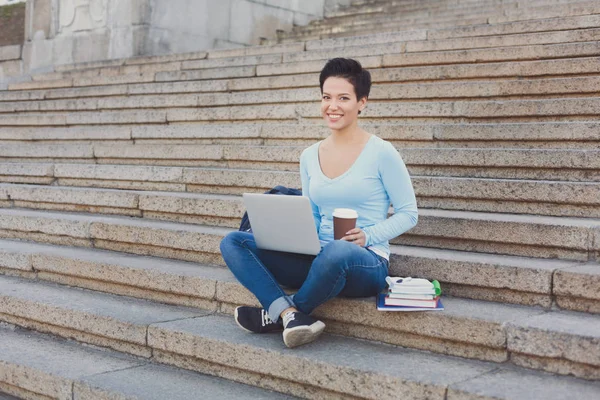 Student dívka sedí na schodech s kávou a laptop venku — Stock fotografie