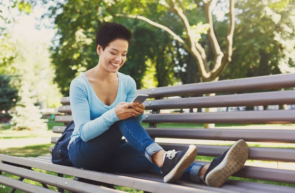 Mujer sonriente escribiendo en el móvil al aire libre — Foto de Stock