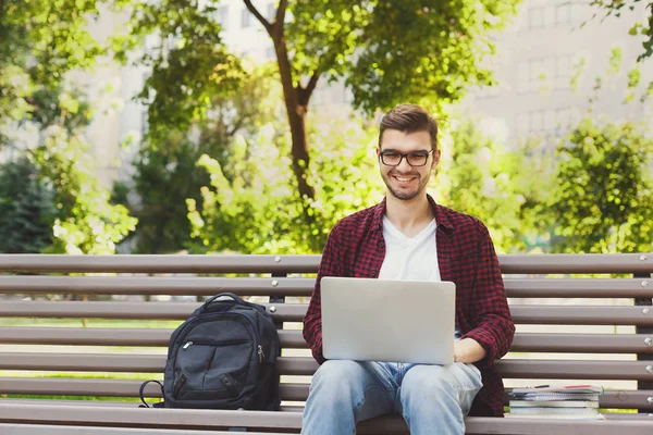 Mutlu bir adam parkta laptop kullanıyor