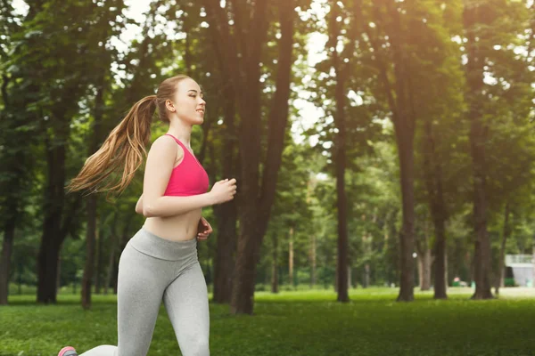 Mujer joven corriendo en el parque verde, espacio de copia — Foto de Stock