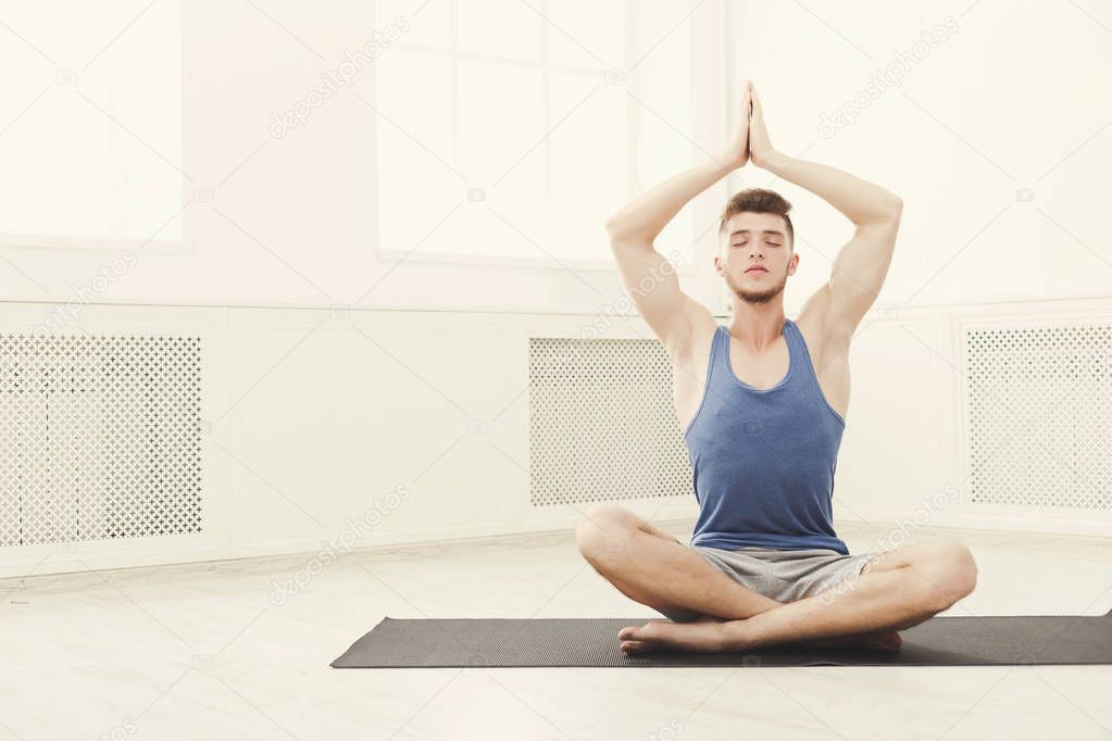 Man training yoga in lotus pose, copy space