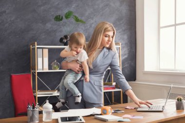 Dizüstü bilgisayar kullanırken genç anne holding bebek