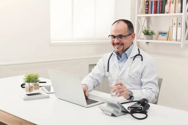 Портрет врача в очках, сидящего за столом — стоковое фото