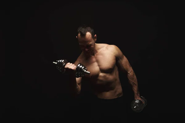 Strong athletic man with dumbbell showes naked muscular body — Stock Photo, Image