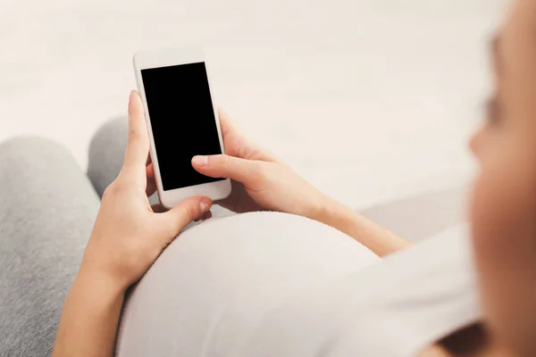 Щаслива вагітна жінка використовує смартфон вдома — стокове фото
