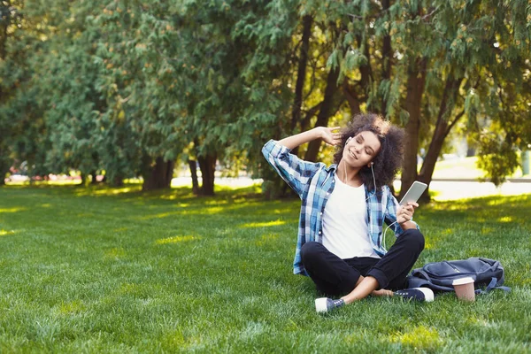Mujer joven escuchando música en la hierba al aire libre —  Fotos de Stock