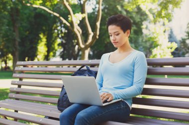 Dizüstü bilgisayar açık havada oturma kullanan genç kadın