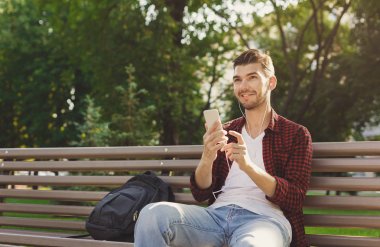 Açık havada oturma ve smartphone kullanarak mutlu genç yakışıklı adam