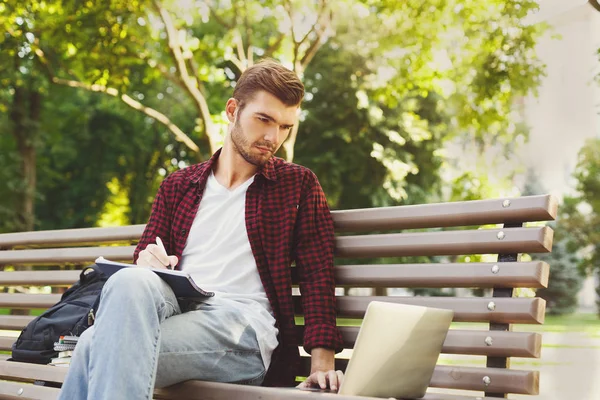 Koncentrerad student som studerar med laptop och bärbara utomhus — Stockfoto