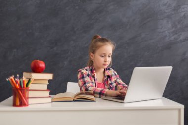 Dizüstü bilgisayarda ödev yapan sevimli küçük kız.