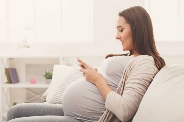Akıllı telefon kullanan mutlu hamile kadın