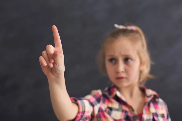 Little girl making gesture at black background — Stock Photo, Image