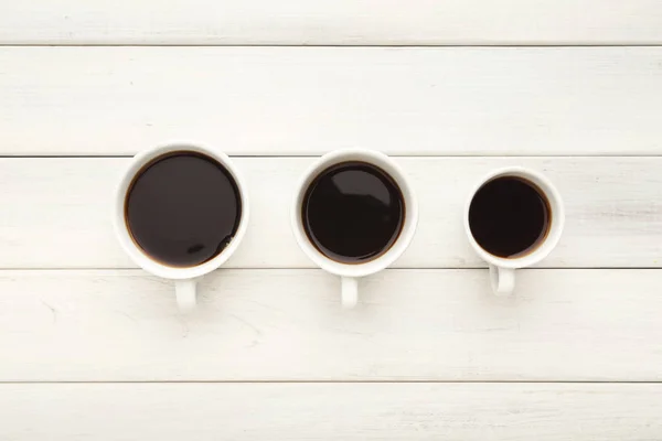 白い木製のテーブルにブラック コーヒーと様々 なカップ — ストック写真
