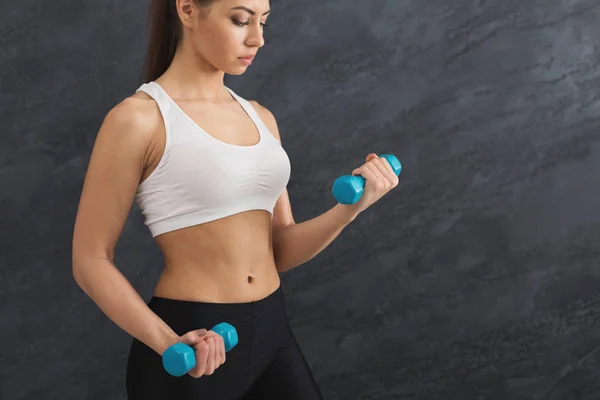 Modelo fitness mujer con mancuernas sobre fondo gris — Foto de Stock