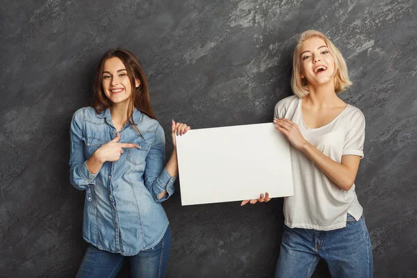 Filles heureuses avec bannière blanche vierge au fond sombre studio — Photo