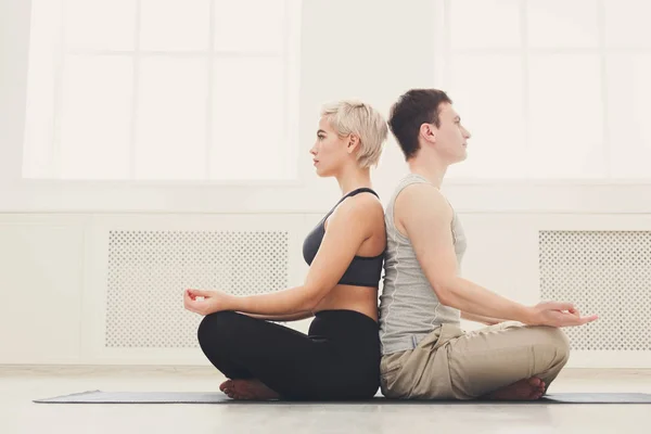 Young couple meditating together, back to back — Stock Photo, Image