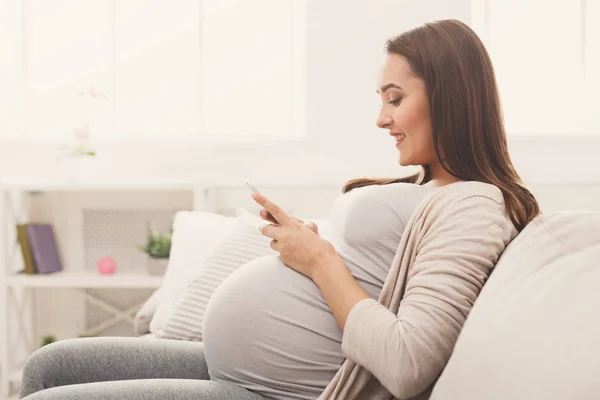 Щаслива вагітна жінка використовує смартфон — стокове фото