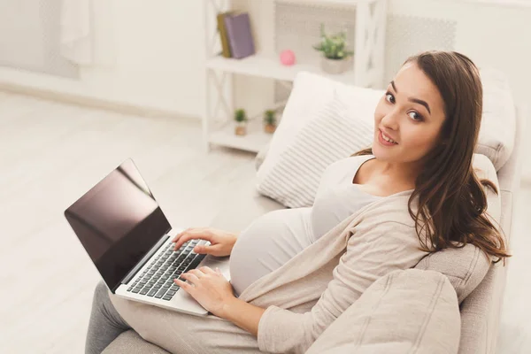 Щаслива вагітна жінка використовує ноутбук вдома — стокове фото