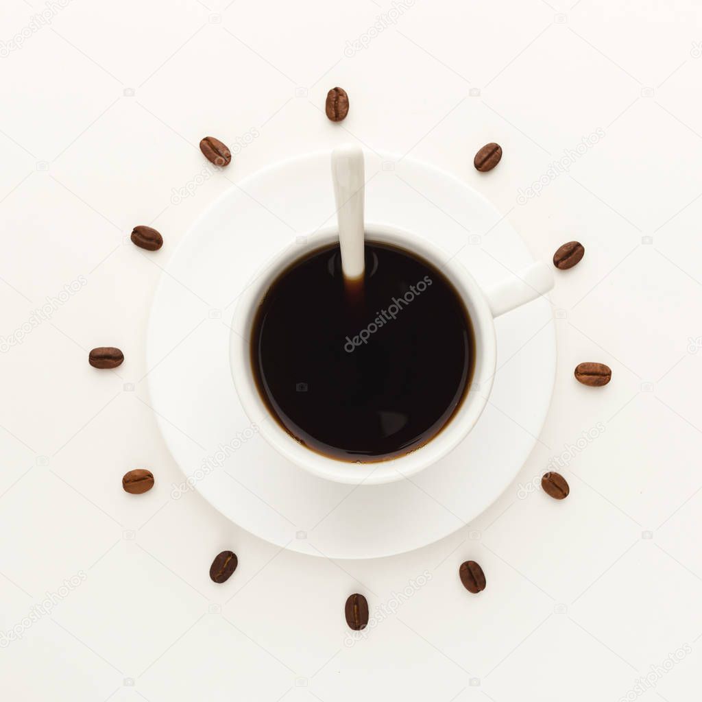Black coffee cup and roasted beans forming clock dial isolated on white