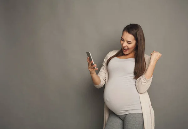 Mujer embarazada sorprendida usando smartphone — Foto de Stock