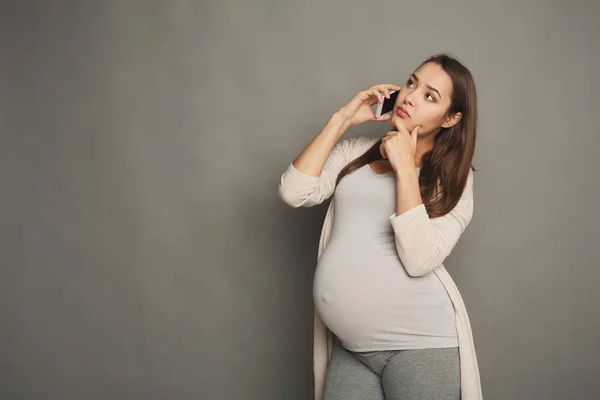 Mujer embarazada pensativa hablando en espacio de copia del teléfono —  Fotos de Stock