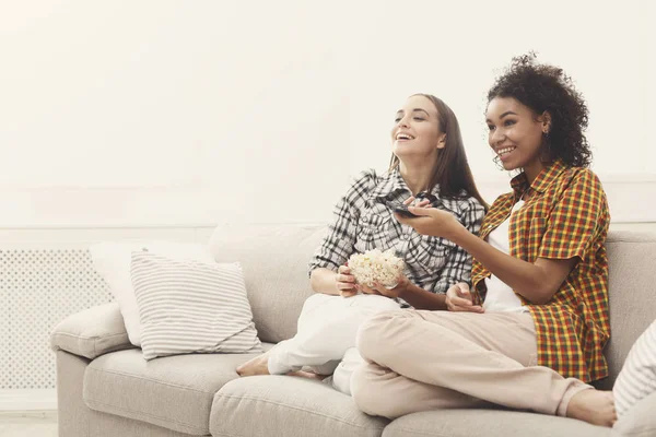 Улыбающиеся молодые женщины смотрят телевизор дома — стоковое фото