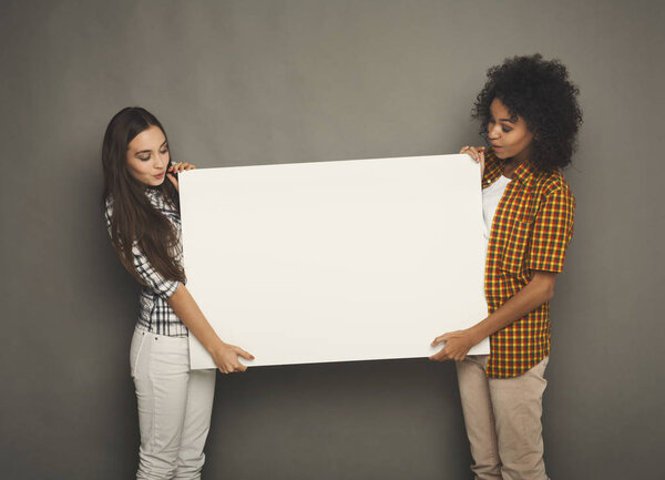 Two girlfriends holding blank white banner