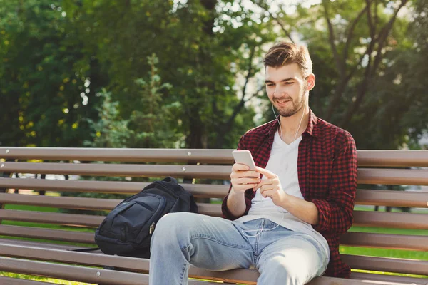 Szczęśliwy młody mężczyzna na zewnątrz przy użyciu smartfona — Zdjęcie stockowe