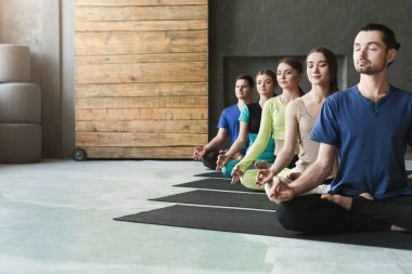 Genç kadın ve erkek yoga sınıfındaki rahatla meditasyon poz
