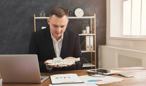 Financier man zitten in kantoor en het aanhouden van geld in de hand — Stockfoto