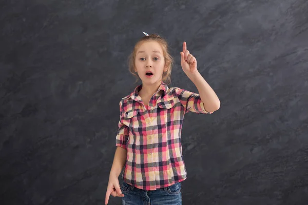 Casual little girl showing finger up at gray background — Stock Photo, Image