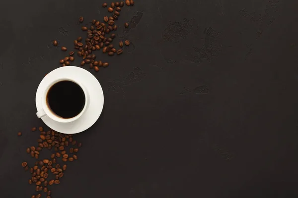 Cup of black coffee and scattered beans on gray background — Stock Photo, Image